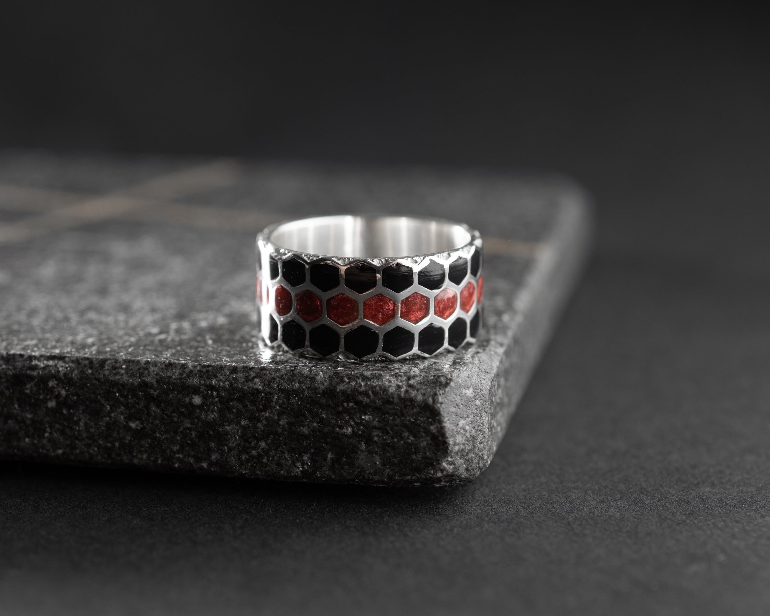 Silver ring with honeycomb pattern on a dark surface